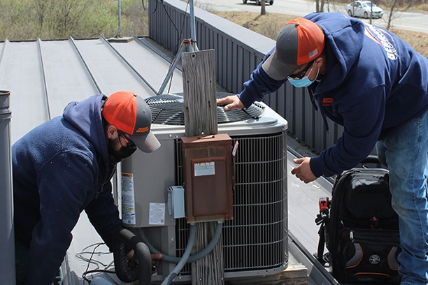 Technicians installing mini-split unit rooftop New Hampshire