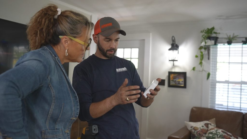 Technician showing thermostat to woman indoors